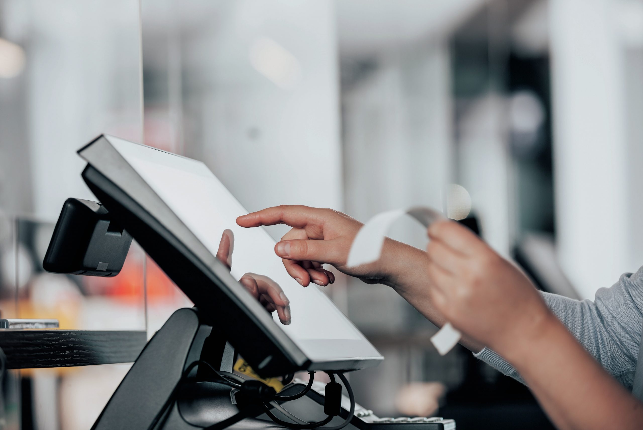 Sales assistant's hands operate a touch-screen till.