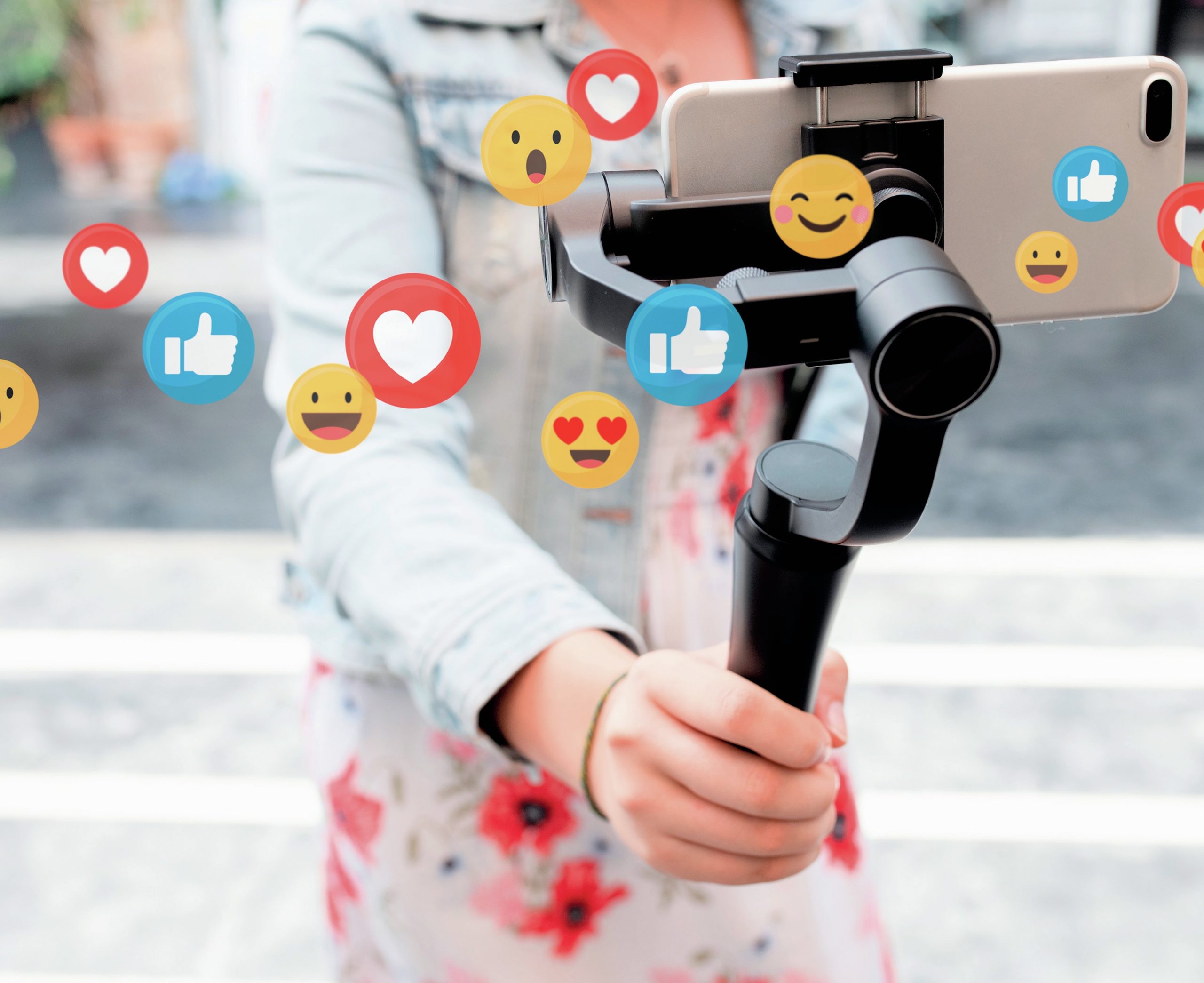 Influencer holding phone with a foreground of emojis.