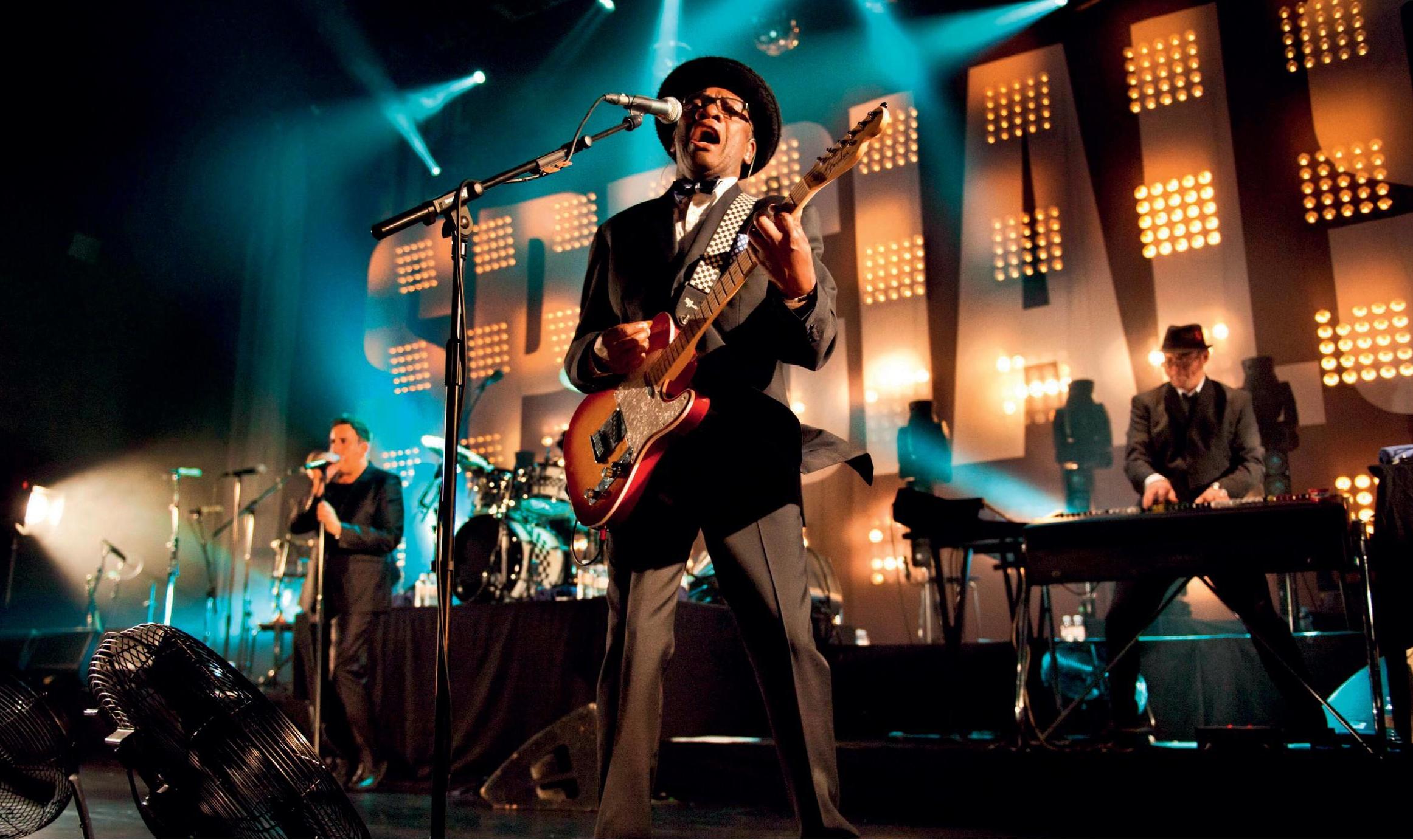 Band on stage, singing and playing instruments.