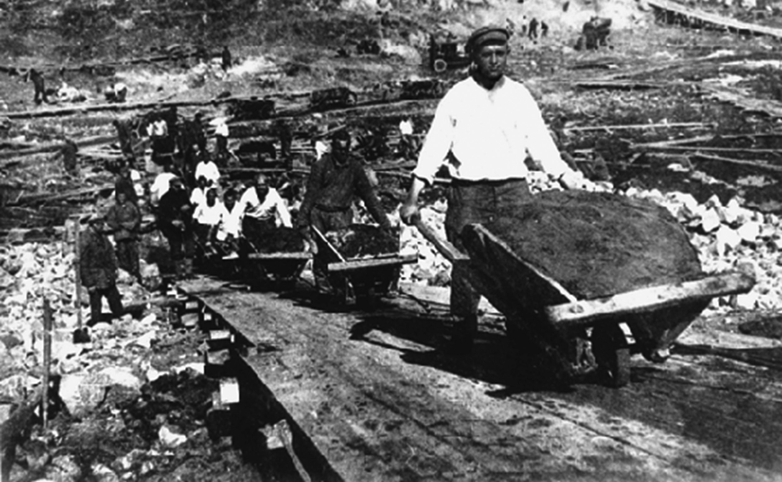 Monochrome photo of Gulag prisoners pushing wheelbarrows.