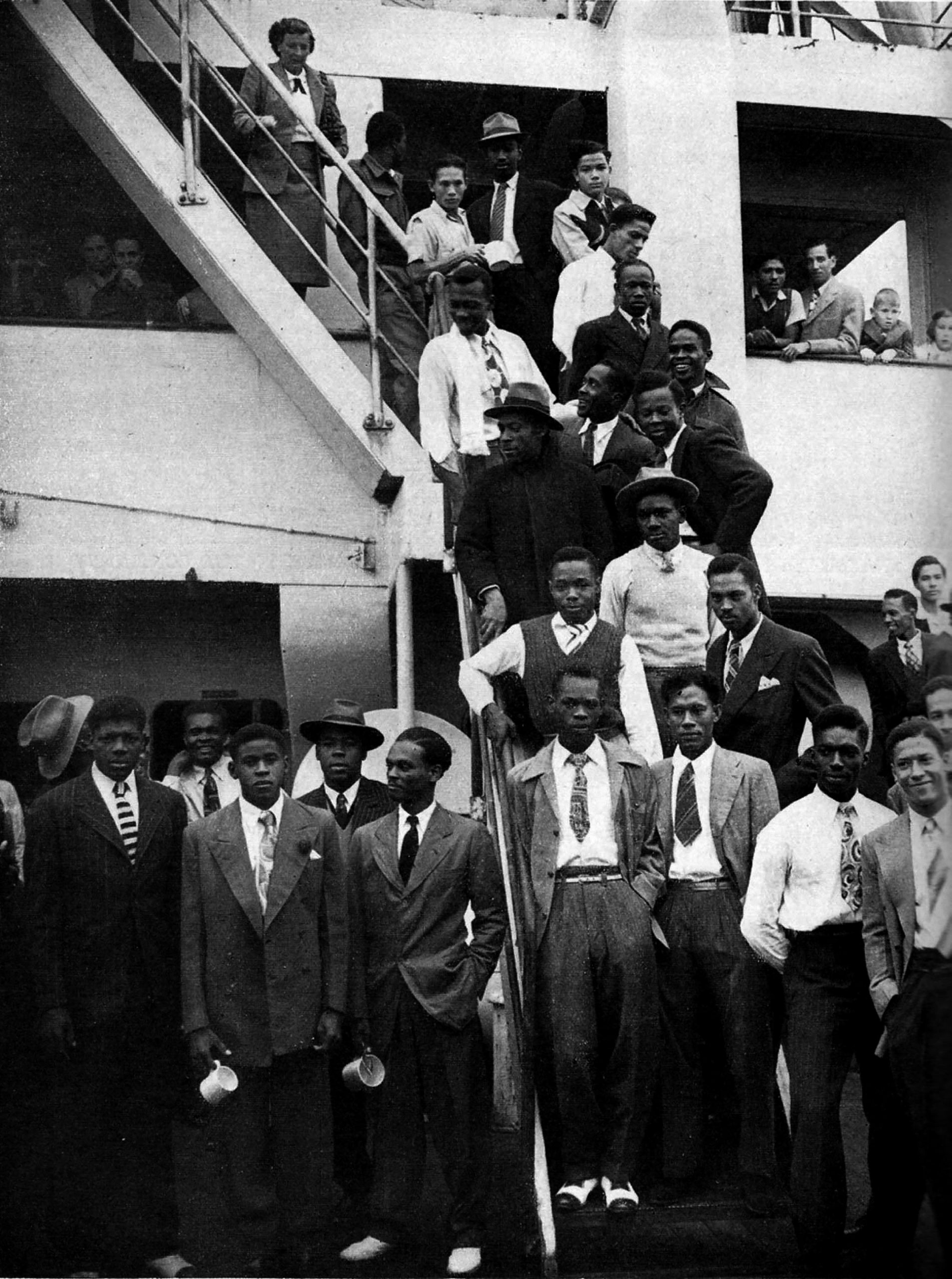 Group of men and women pose on the steps of a boat.