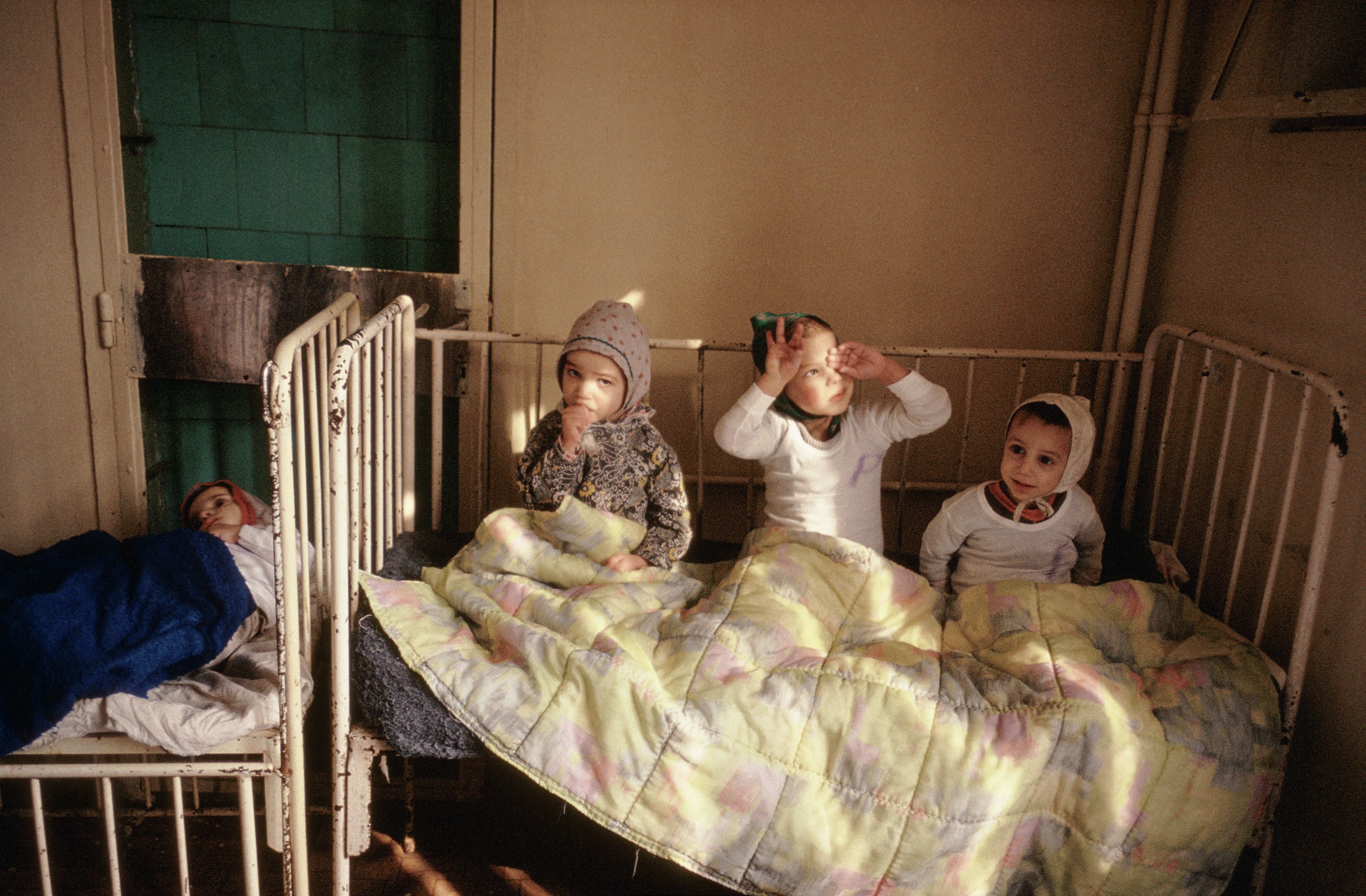 Historical image of Romanian children sharing a cot.