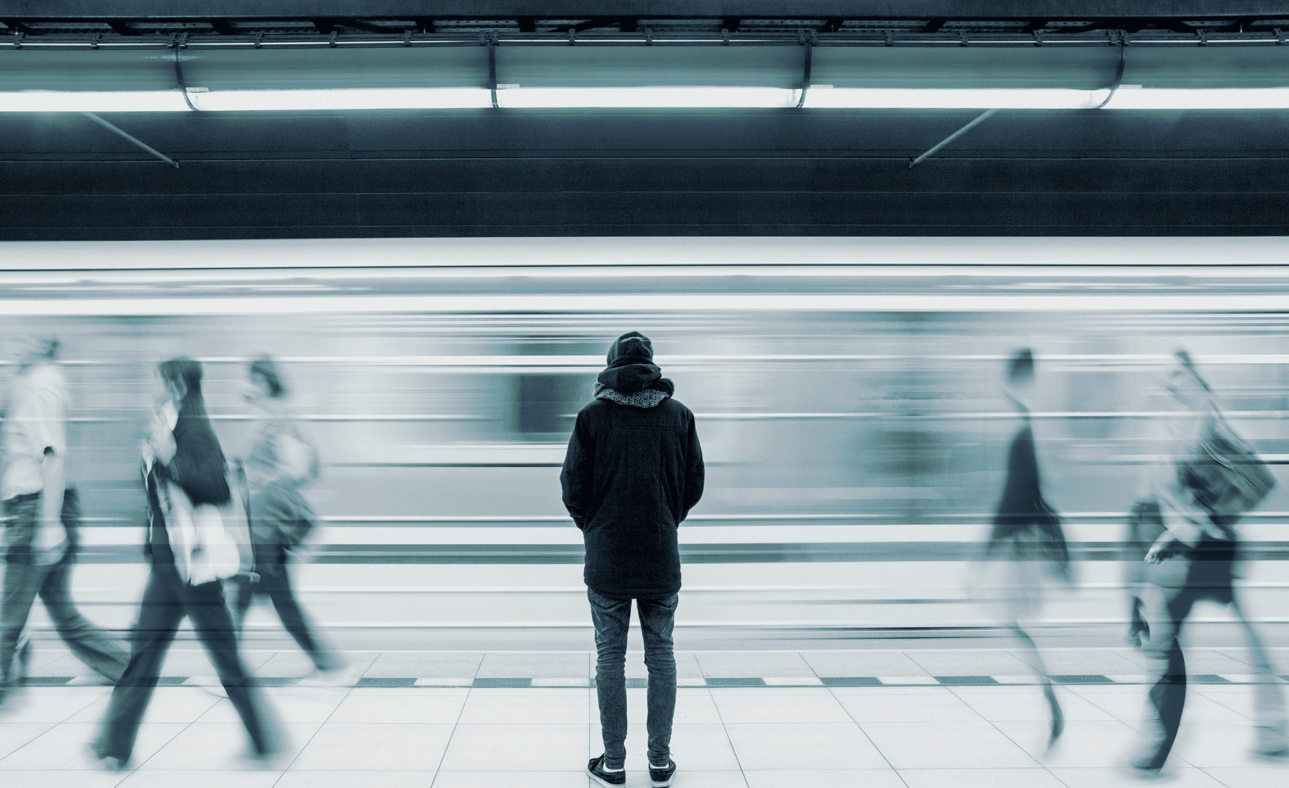 Man stands motionless on an underground platform.