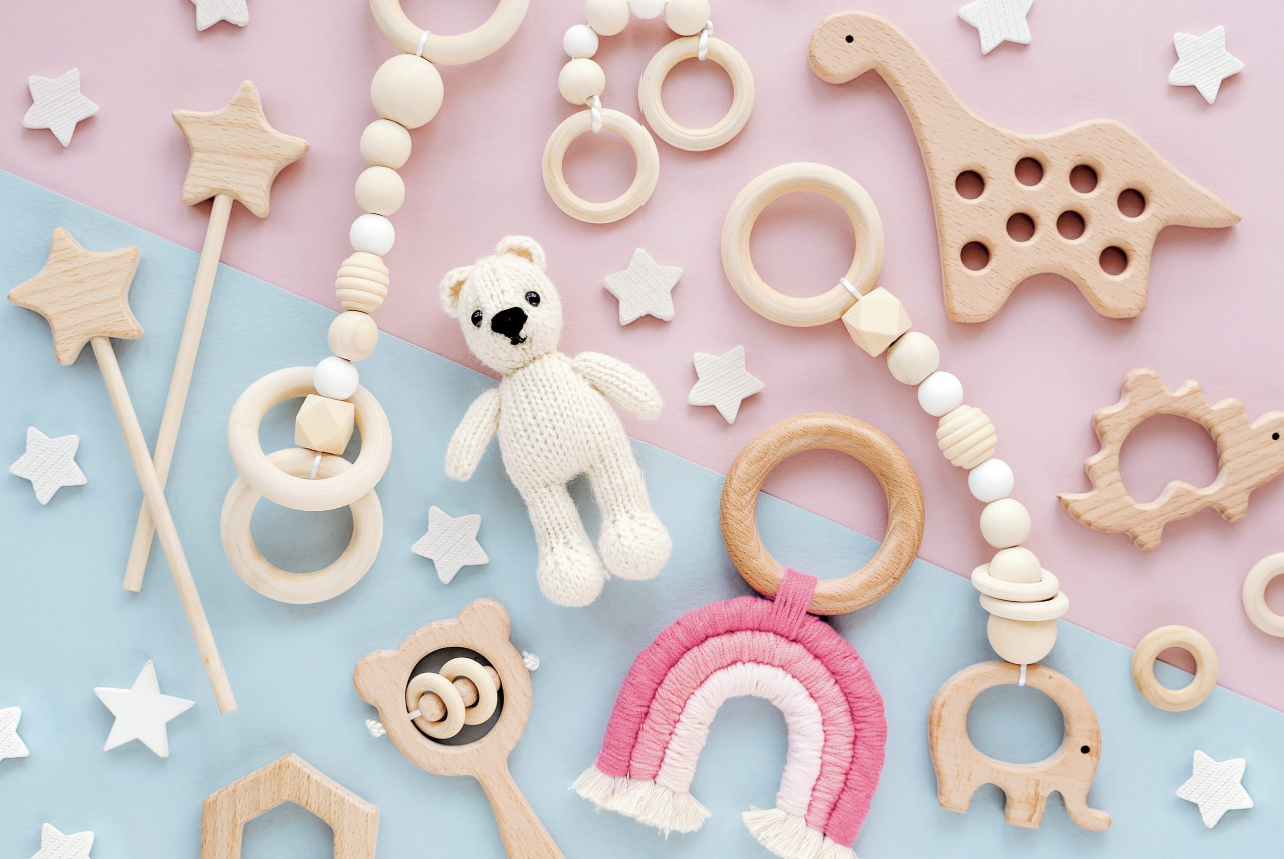 Selection of wooden baby toys on a blue and pink background.