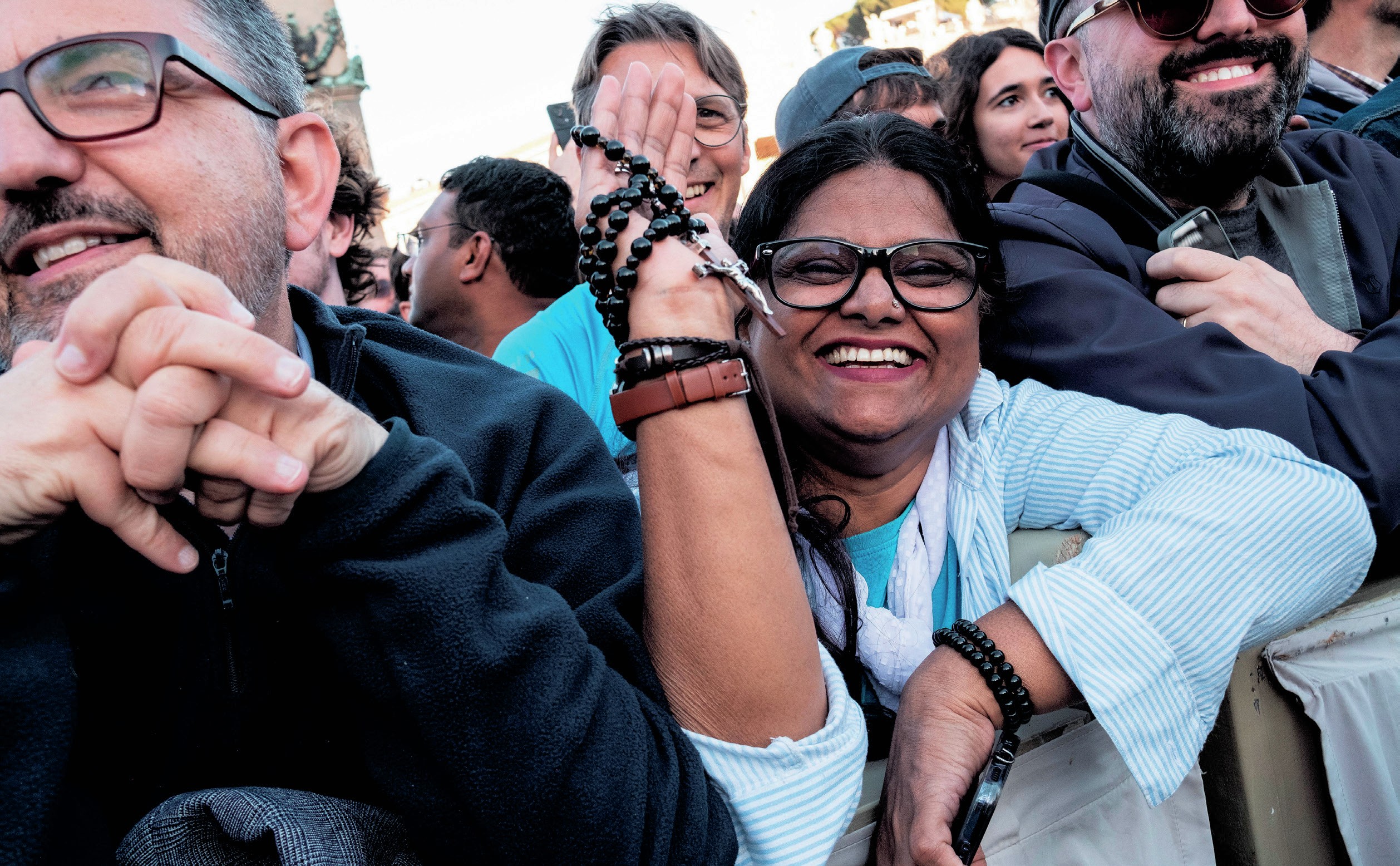 Happy crowd holding rosary beads.