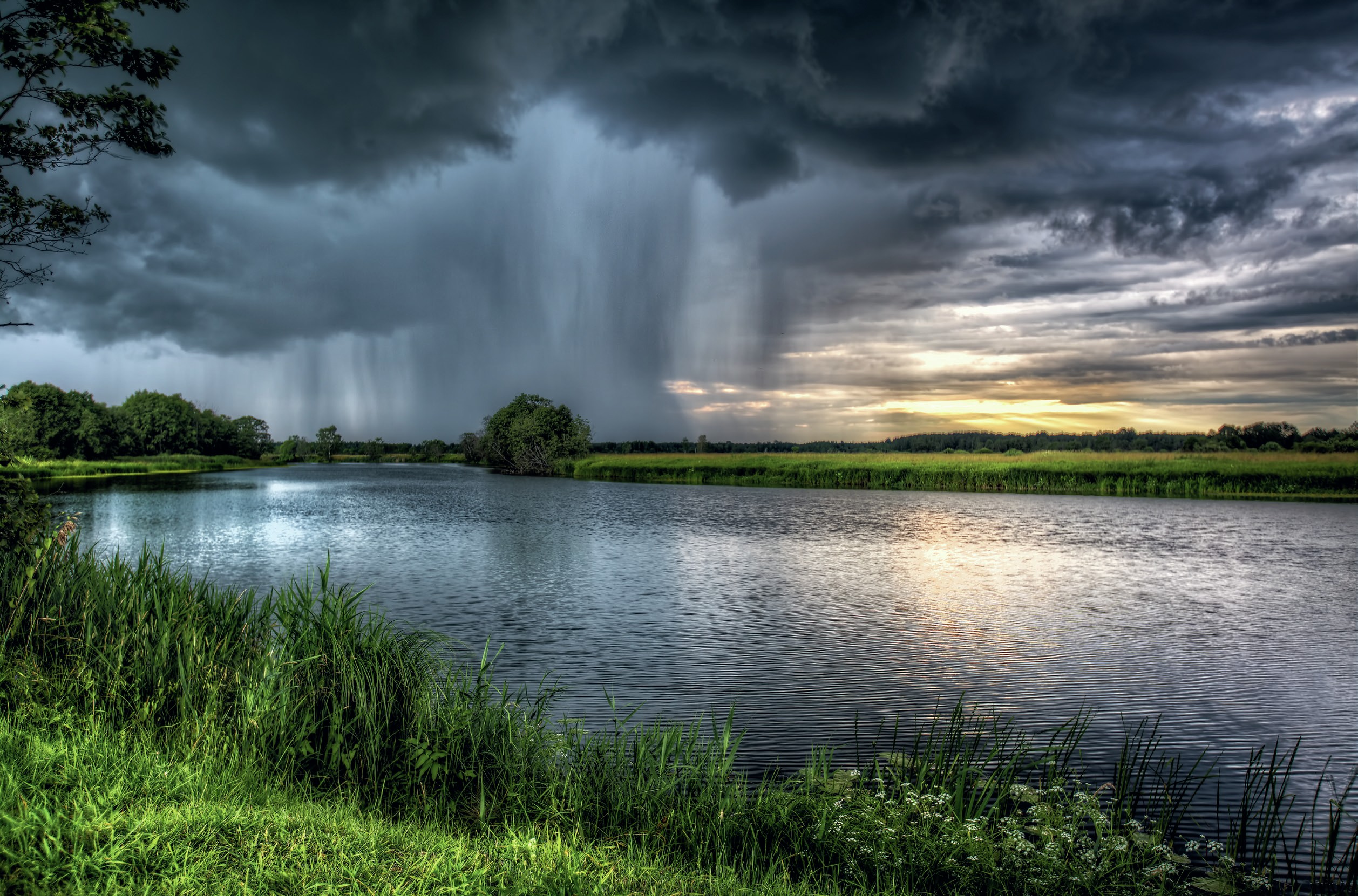 Rain falls in the background of a riverside location.