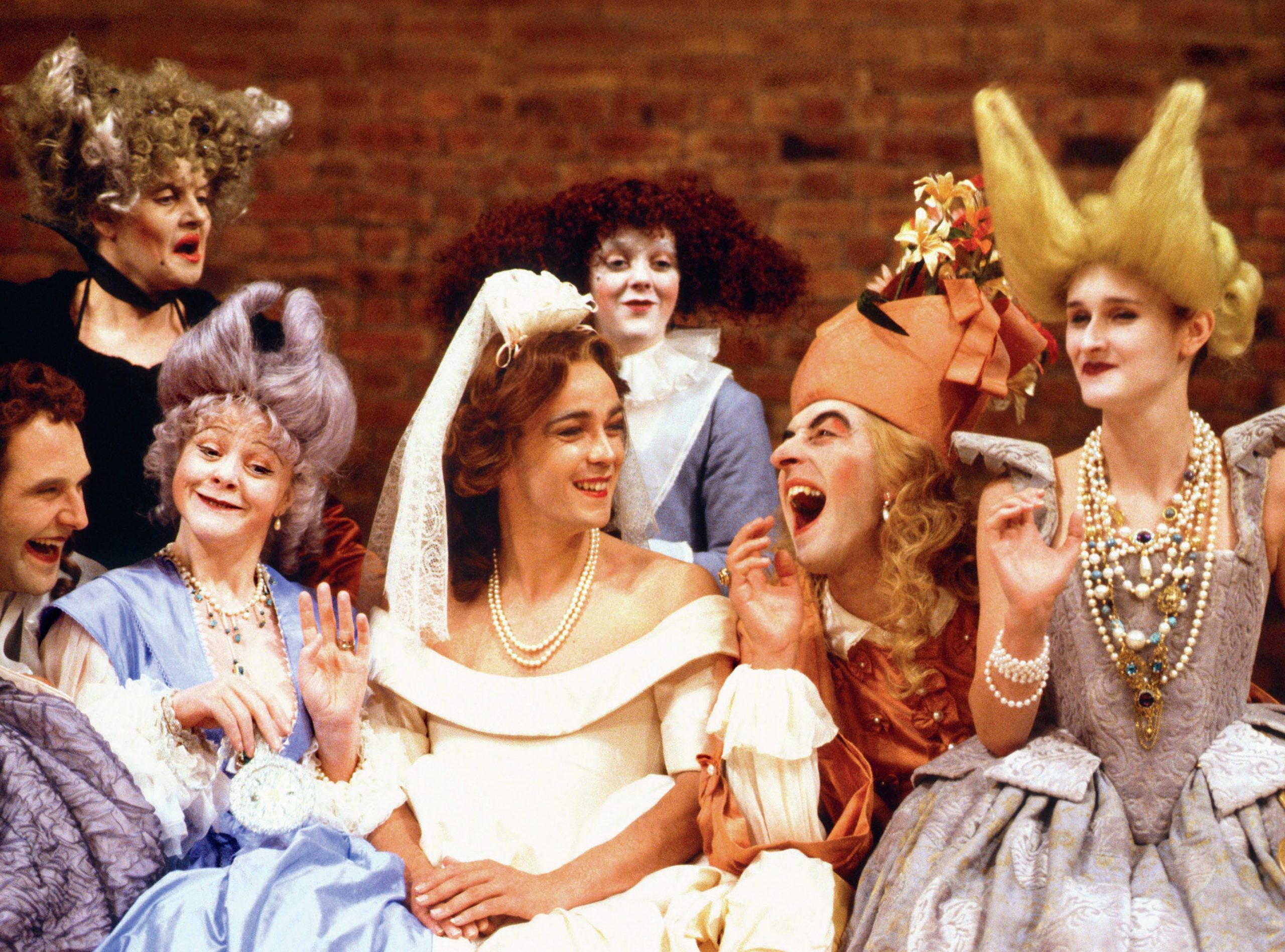 Seven men dressed up as women, including Epicoene in a wedding dress.