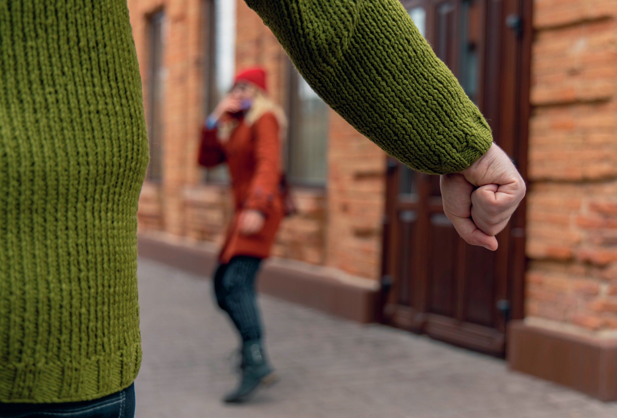 Clenched fist in foreground with woman reacting in the background.