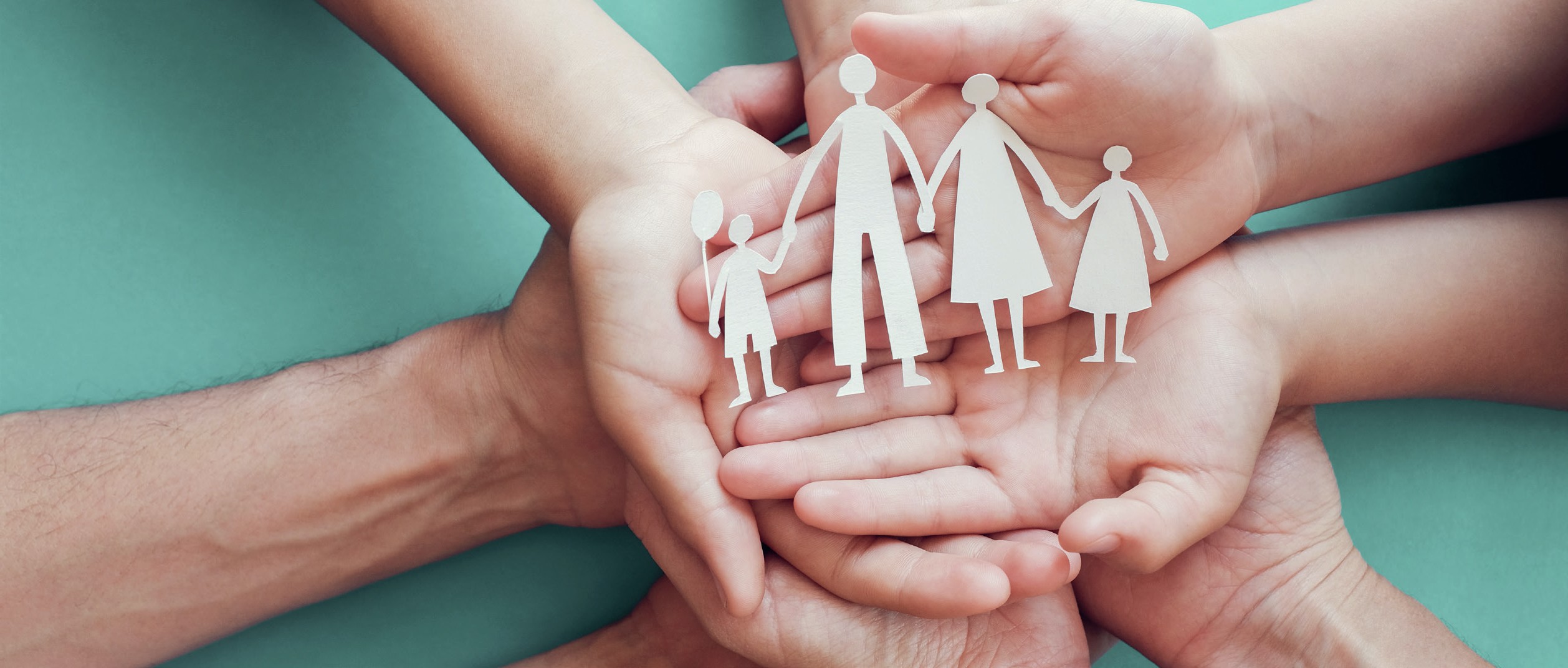 Hands holding paper dolls depicting a family of four.