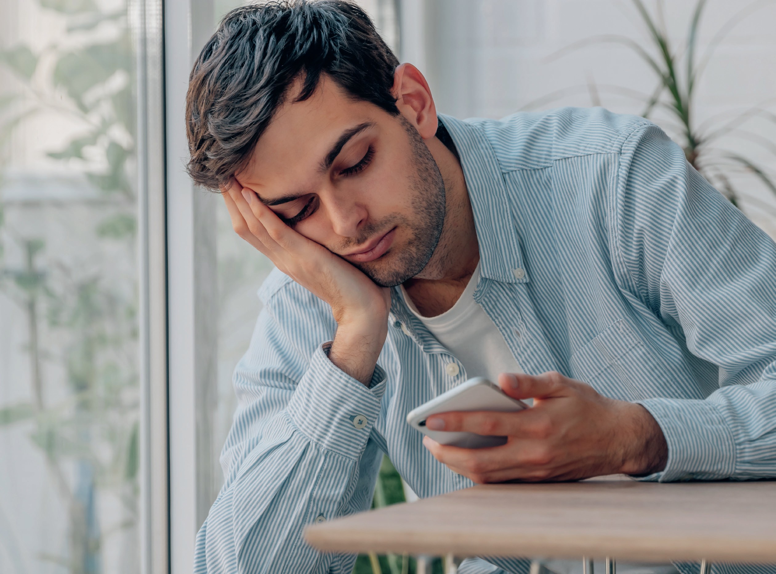 Bored young man glances down at his phone.