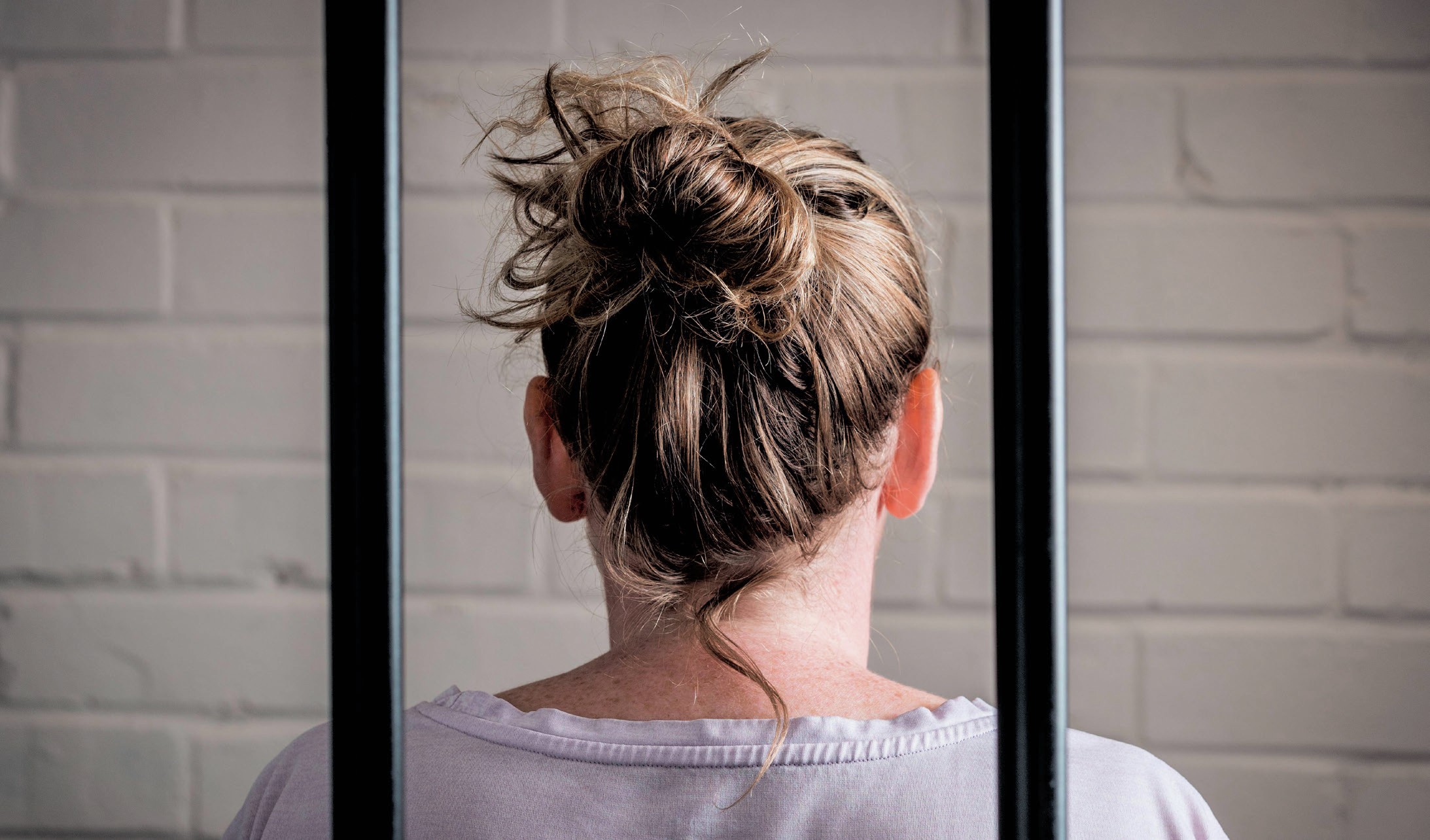 Back of woman's head behind bars.