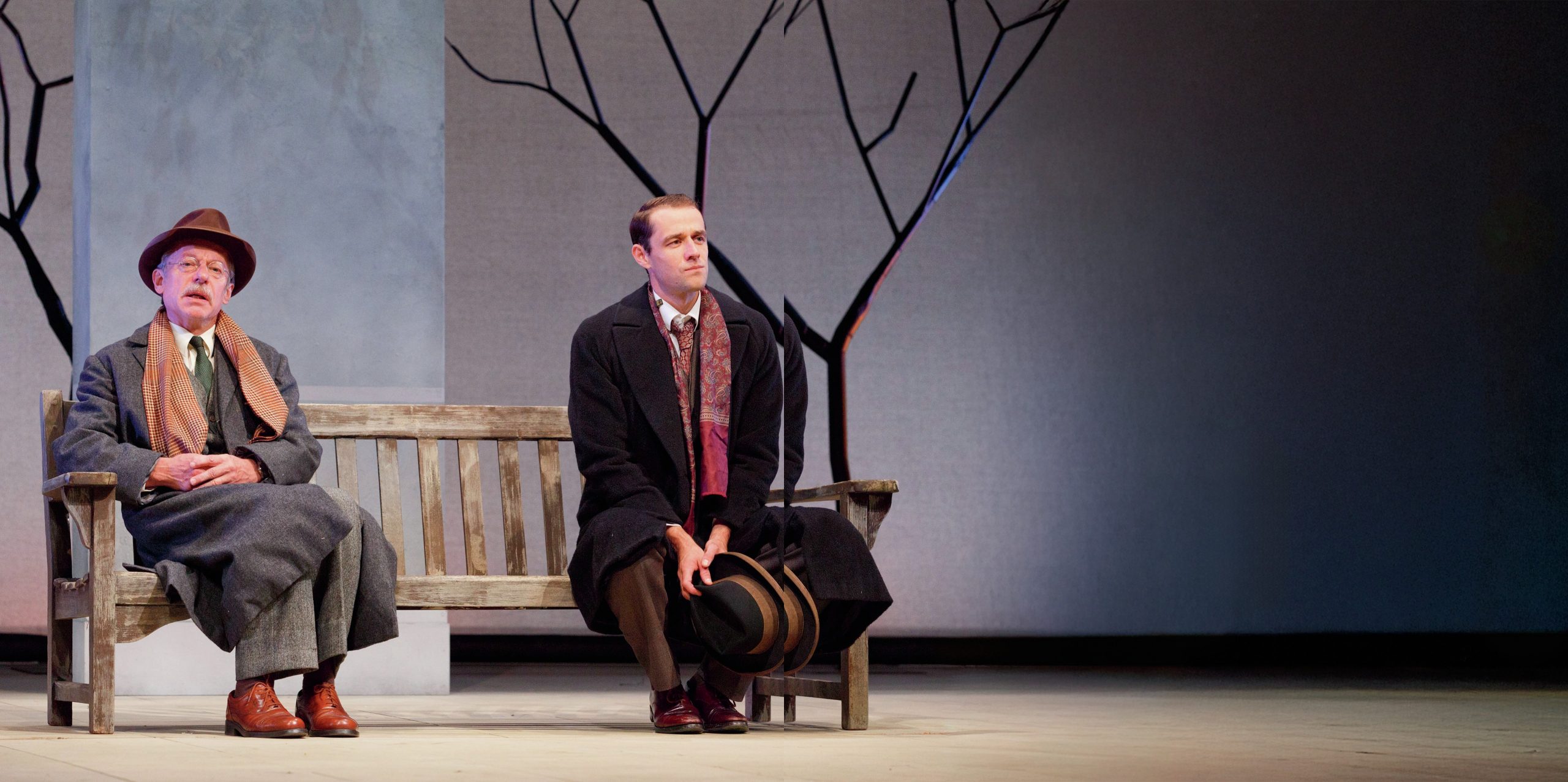 The two men are sitting next to each other at either end of a park bench