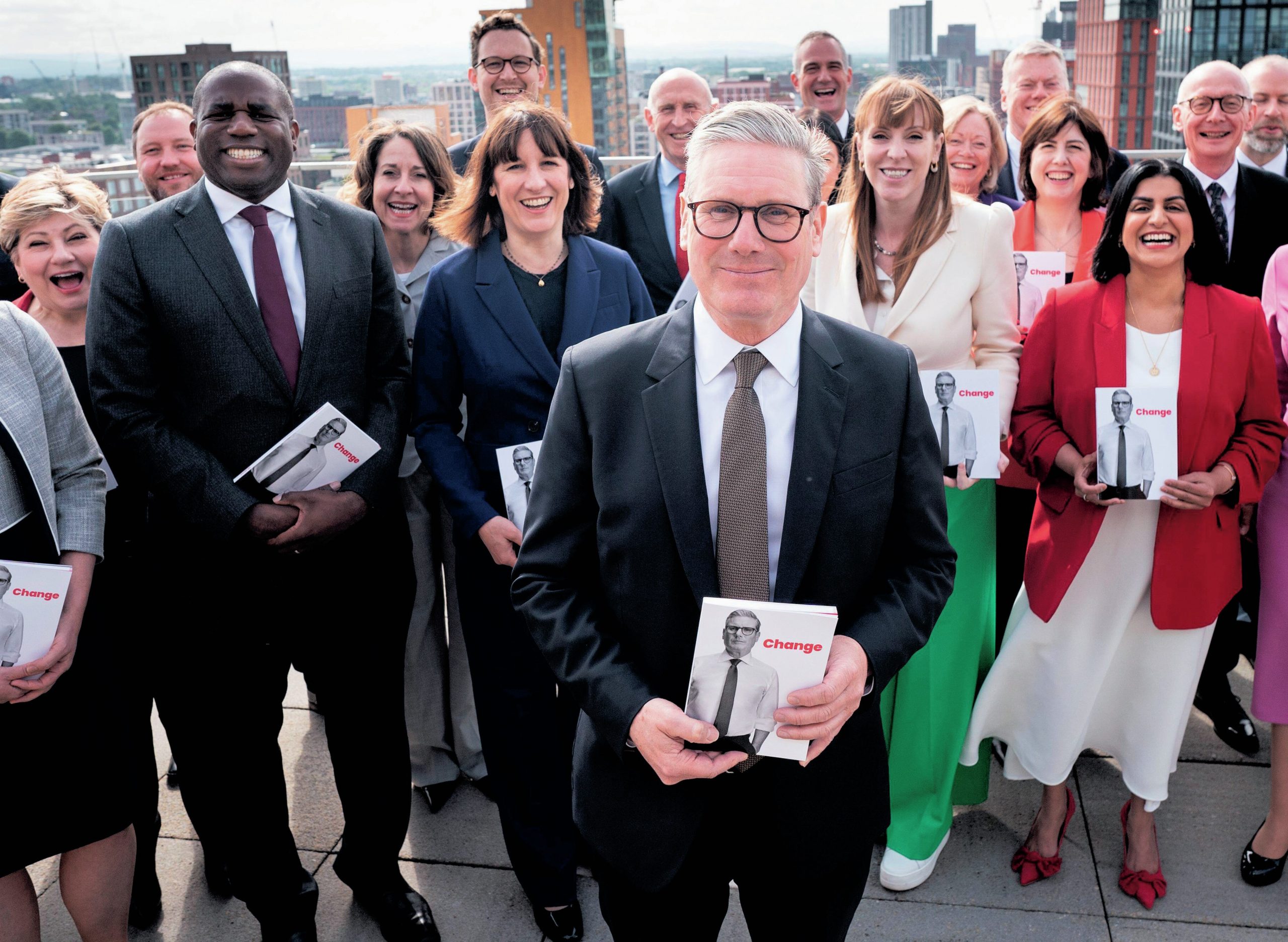 Starmer standing in the foreground holding the manifesto, with other MPs behind him.