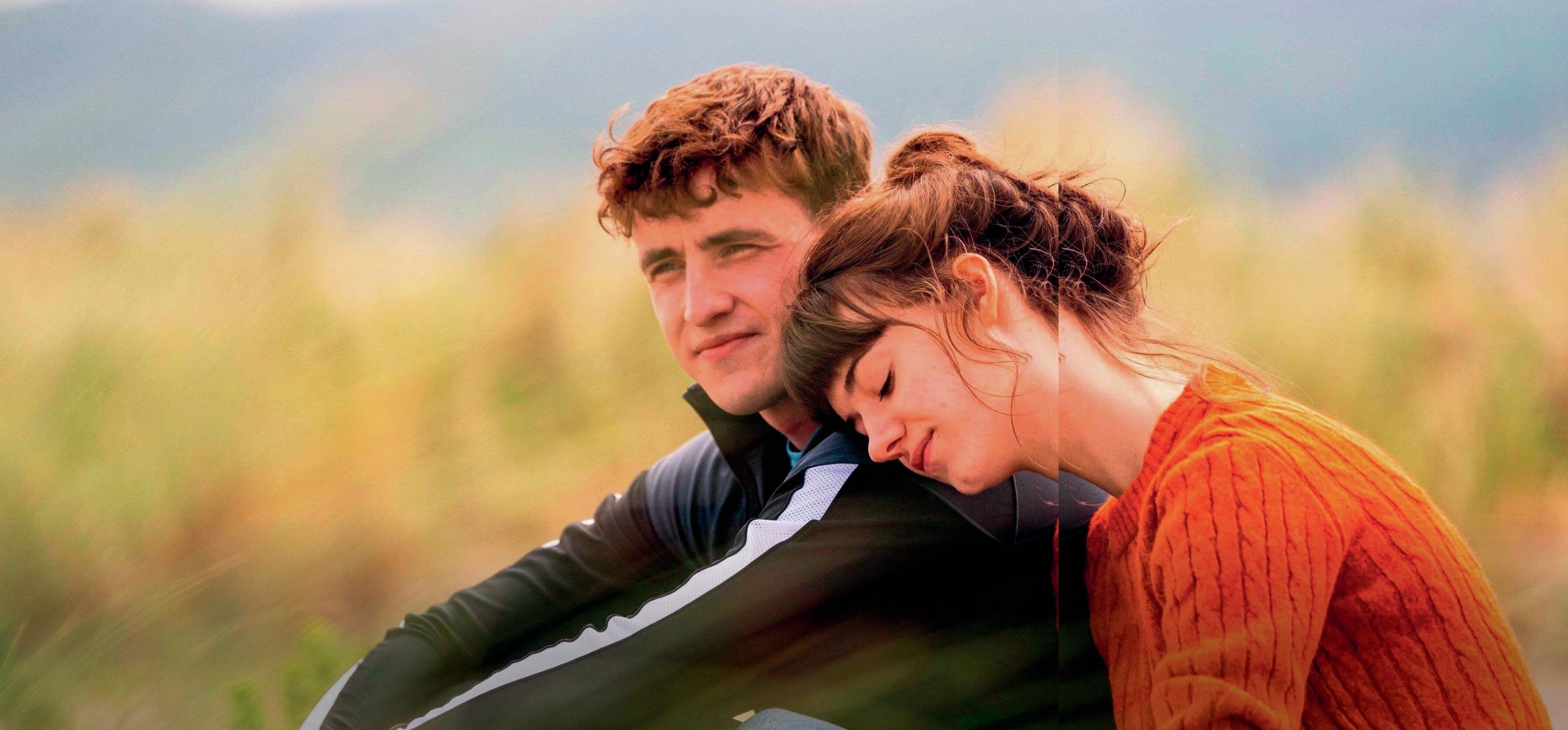 Characters are sitting outside on the ground, and Marianne is resting her head on Connell’s shoulder.