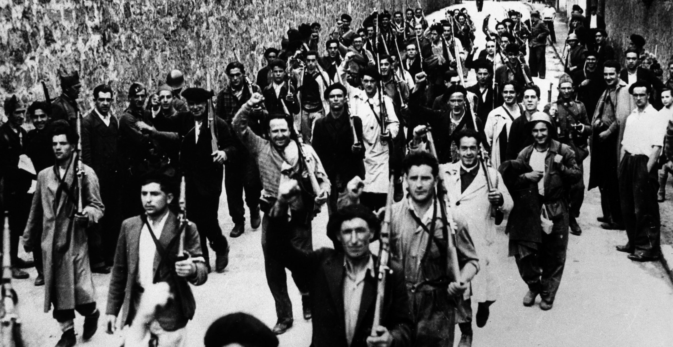 A crowd of people carrying guns walking down a road.